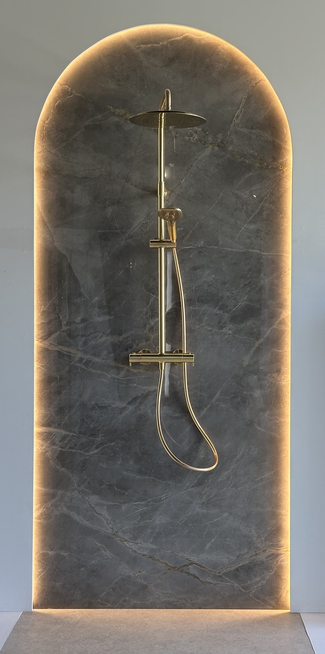 Faïence effet marbre en arche rétro-éclairée dans une douche du showroom